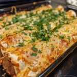 Close-up of golden, cheesy chicken enchiladas topped with red sauce and cilantro.
