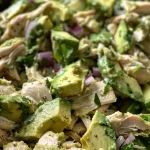 A close-up shot of a vibrant avocado chicken salad with diced avocados and shredded chicken.