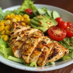 Close-up of a grilled chicken avocado salad in a bowl, showcasing vibrant ingredients.