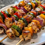 Close-up side view of juicy grilled chicken skewers with colorful vegetables.