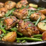 Close-up view of a one-pan chicken dinner featuring green beans and potatoes.