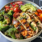 A close-up side view of a colorful Fresh Tomato & Chicken Veggie Bowl, showcasing diced chicken, vibrant greens, and sliced tomatoes.