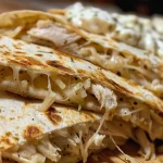 Close-up of a juicy Chicken Alfredo Quesadilla, showing melted cheese and diced chicken.