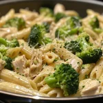 A close-up view of creamy broccoli and chicken penne pasta in a bowl.