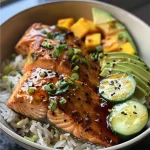 A close-up view of a vibrant Garlic Ginger Salmon Bowl featuring salmon, avocado, cucumber, and mango.