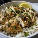 Close-up of Garlic Herb Chicken Rice Bowls topped with fresh parsley and lemon wedges.