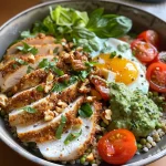 Close-up of a colorful Green Goddess Grain Bowl topped with crispy chicken, cherry tomatoes, and fresh herbs.
