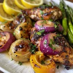 Close-up side view of juicy lemon garlic chicken pieces on a plate with yogurt sauce.