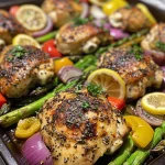 Juicy lemon garlic chicken thighs with colorful vegetables on a sheet pan.