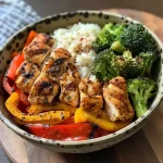 Close-up view of a balanced chicken and veggie power bowl featuring colorful vegetables and rice.