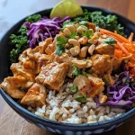 Close-up view of a Buddha Bowl featuring Thai chicken, colorful vegetables, and a creamy sauce.