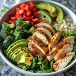 A colorful chicken veggie bowl featuring diced red bell peppers, steamed broccoli, and sliced zucchini.