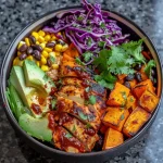 A vibrant BBQ Chicken Sweet Potato Bowl with diced chicken, sweet potatoes, avocado, corn, black beans, and garnishes.