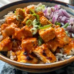 A close-up view of a Buffalo Chicken Rice Bowl featuring diced chicken, rice, beans, and toppings.