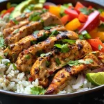 Close-up of Cajun chicken served on a bed of coriander and lime rice with colorful bell peppers.