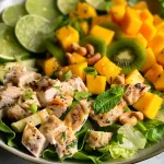 Close-up view of a vibrant Chicken Kiwi Mango Salad featuring diced chicken, kiwi, and mango on a bed of romaine.
