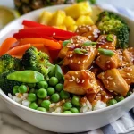 A close-up view of a colorful chicken teriyaki pineapple bowl with chunks of chicken, pineapple, and rice.