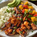 A close-up view of grilled chicken bites glazed in maple sriracha on a bed of coconut rice with vibrant mango avocado salsa.