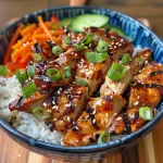 Close-up of a Korean BBQ chicken bowl with gochujang cream sauce, garnished with green onions and sesame seeds.