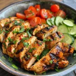 Close-up view of a Lemon Chili Grilled Chicken Bowl featuring diced chicken, cucumber salad, and hummus.