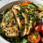Close-up of a vibrant Lemon Herb Chicken Quinoa Bowl with colorful vegetables.