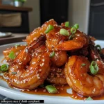 Close-up view of succulent honey glazed shrimp, garnished with green onions and sesame seeds.