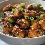 Close-up view of juicy Sweet Chili Chicken on a plate, garnished with green onions and sesame seeds.