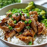 Juicy Teriyaki chicken pieces on a bed of rice with colorful vegetables.