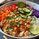 Close-up view of a colorful Thai Peanut Chicken Bowl featuring chicken, vegetables, and rice.