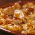 Creamy mac and cheese with chunks of honey BBQ chicken, viewed from the side.