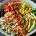 ['Close-up view of a colorful Buffalo Chicken Burrito Bowl with chicken, rice, and fresh toppings.', 'Side view of a delicious Buffalo Chicken Burrito Bowl filled with vibrant ingredients and textures.', 'Juicy Buffalo Chicken Burrito Bowl featuring sliced chicken, avocado, tomatoes, and cheese.', 'A hearty serving of Buffalo Chicken Burrito Bowl displaying layers of rice, beans, and fresh herbs.']