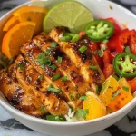 ['Juicy Cajun Honey Chicken Bowl with colorful vegetables on a plate.', 'Close-up of a spicy Cajun chicken bowl garnished with orange slices and green onions.', 'Side view of Cajun Honey Chicken Bowl showcasing vibrant ingredients and glossy sauce.', 'Succulent pieces of chicken in a bowl with red and green peppers and honey glaze.']