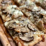 ['Close-up of a Chicken and Mushroom Flatbread topped with melted cheese and herbs.', 'Side view of juicy Chicken and Mushroom Flatbread, showcasing chicken, mushrooms, and cheese.', 'Delicious Chicken and Mushroom Flatbread with a crispy base and fresh ingredients.', 'A mouthwatering Chicken and Mushroom Flatbread, highlighting the savory toppings and golden edges.']