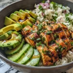 ['Close-up view of a colorful bowl featuring Chili Lime Chicken with avocado, cucumbers, and rice.', 'A vibrant dish of Chili Lime Chicken Avocado Bowl, showcasing chopped chicken, avocado, and fresh vegetables.', 'Side view of a Chili Lime Chicken Avocado Bowl filled with rice, diced cucumbers, and a sprinkle of cilantro.', 'Detailed image of a delicious bowl with juicy chicken, avocado, and mixed vegetables, garnished with cilantro.']
