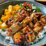 ['A close-up view of a Glazed Chicken Mango Bowl featuring juicy chicken, diced mango, and colorful toppings.', 'A vibrant bowl of Glazed Chicken with mango, garnished with cilantro and red chili, presented side-on.', 'An appetizing side view of a Glazed Chicken Mango Bowl showcasing chicken, rice, and fresh mango chunks.', 'A detailed image of a delicious Glazed Chicken Mango Bowl with bright colors and textured ingredients.']