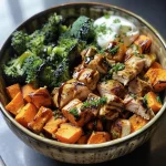 ['Close-up of a bowl featuring crispy chicken, roasted sweet potato, and broccoli.', 'Side view of a delicious crispy chicken bowl with vibrant sweet potatoes and green broccoli.', 'Juicy crispy chicken served with colorful roasted sweet potatoes and a drizzle of balsamic vinegar.', 'A healthy bowl showcasing succulent chicken, cubed sweet potatoes, and broccoli florets.']