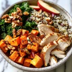 ['A close up of a cozy autumn grain bowl filled with wild rice, quinoa, chicken, sweet potatoes, kale, and apples.', 'A detailed side view of a colorful grain bowl showcasing ingredients like diced sweet potatoes, kale, and nuts.', 'An inviting autumn grain bowl featuring cooked quinoa, wild rice, shredded chicken, and fresh apple cubes.', 'A vibrant display of a grain bowl with roasted sweet potatoes, greens, and a drizzle of maple cinnamon vinaigrette.']