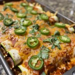 ['Close-up of zucchini wrapped chicken enchiladas topped with salsa and avocado.', 'Juicy chicken enchiladas wrapped in zucchini, garnished with jalapeño and cilantro.', 'Side view of delicious zucchini wrapped chicken enchiladas with a colorful topping.', 'Close-up image of zucchini enchiladas filled with shredded chicken and fresh ingredients.']