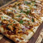 A close-up view of a BBQ Ranch Chicken Flatbread topped with melted cheese and colorful toppings.