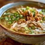 Close-up view of a steaming bowl of Simple Chicken Soup with visible chunks of chicken and vegetables.