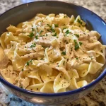 Close-up image of creamy chicken and noodles with shredded rotisserie chicken and egg noodles.